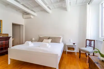 a white bedroom with a white bed and a chair at iFlat Spanish Steps Peaceful Apartment in Rome