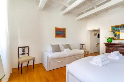 a white room with two beds and a chair at iFlat Spanish Steps Peaceful Apartment in Rome