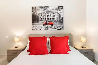 a bedroom with red pillows and a painting on the wall at Clodio Welcome - 5 camere arredate con bagno interno - zona comune - condizionatori - in Rome