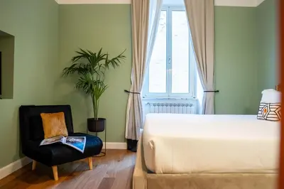 a bedroom with a bed and a chair and a window at NAMAN HOTELLERIE - Monti in Rome