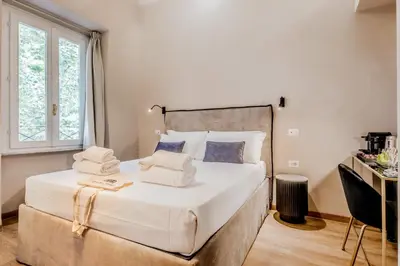 a bedroom with a large bed with white sheets and pillows at Queen of Rome Luxury Rooms in Rome