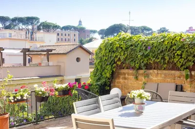 a white table and chairs on a balcony with flowers at Appartamento Vatican Terrace in Rome