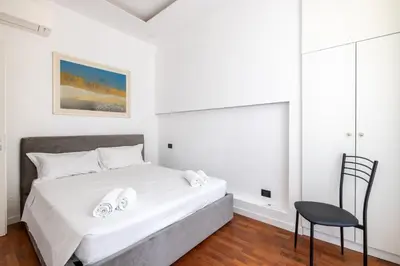 a white bedroom with a bed and a chair at Cavour 211 - B&D Apartments in Rome