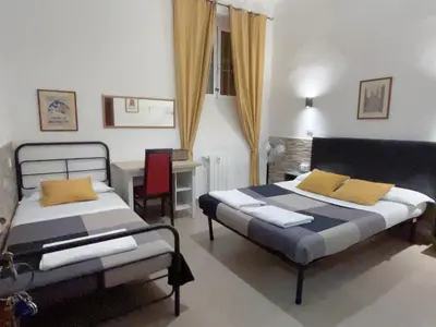 a bedroom with two beds and a table and a desk at Overseas Guesthouse in Rome
