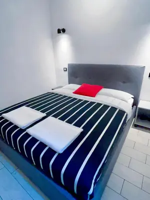 a bed with blue and white sheets and a red pillow at Overseas Guesthouse in Rome