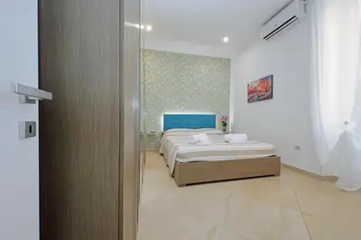 a white bedroom with a bed with a striped blanket at Alba Home Re Di Roma in Rome