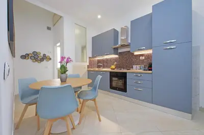 a kitchen with blue cabinets and a wooden table and chairs at Alba Home Re Di Roma in Rome