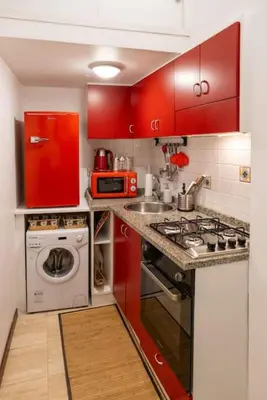 a red kitchen with a sink and a washing machine at Navona Romantic House in Rome