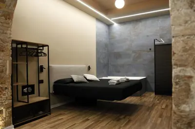 a bedroom with a black bed and a stone wall at Unique Trastevere in Rome