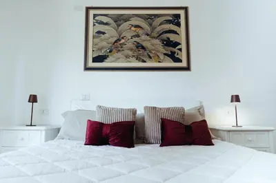 a white bed with red pillows and a picture on the wall at Domus Clelia in Rome
