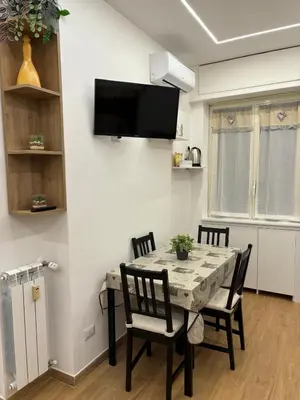 a dining room table with chairs and a television on a wall at Domus Clelia in Rome