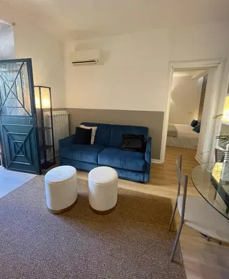 a living room with a blue couch and two white stools at La Casetta di Ponte Milvio con parcheggio in Rome