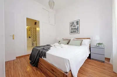 a white bedroom with a large bed and a bathroom at Testaccio - Pretty Apartment in Rome