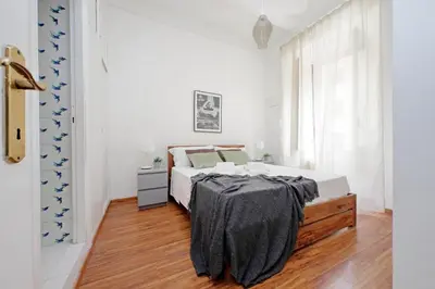 a white bedroom with a bed and a wooden floor at Testaccio - Pretty Apartment in Rome