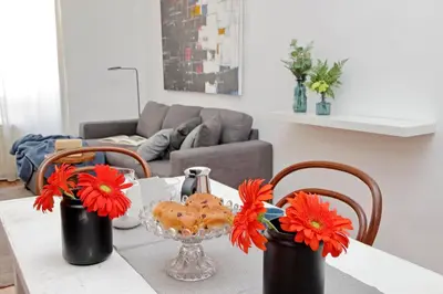 a dining room table with red flowers in black vases at Testaccio - Pretty Apartment in Rome