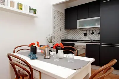 a kitchen with black cabinets and a table with chairs at Testaccio - Pretty Apartment in Rome