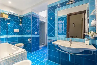 a blue tiled bathroom with a tub and a sink at Hostly-Urban Oasis Turati-Few Steps from Colosseum in Rome