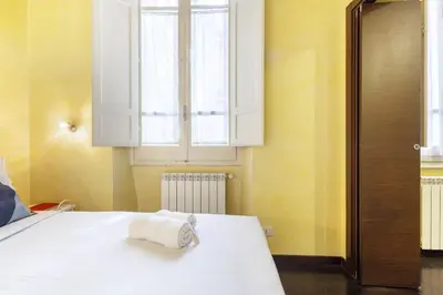 a bedroom with a white bed with a towel on it at Hostly-Urban Oasis Turati-Few Steps from Colosseum in Rome