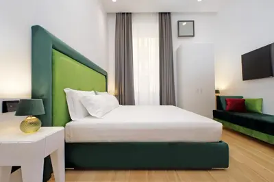 a bedroom with a bed with a green headboard and a couch at Domus Aurea Luxury Suites in Rome