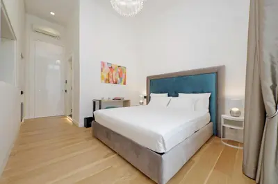 a bedroom with a large white bed with a blue headboard at Domus Aurea Luxury Suites in Rome