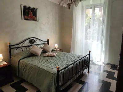 a bedroom with a bed with a green comforter and a window at Iannilli Casa Vacanze in Rome