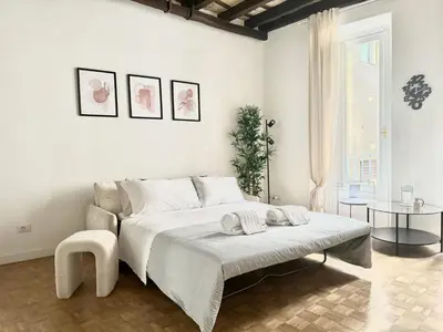 a white bedroom with a large bed and a table at Luxury Apartment Historic Center in Rome