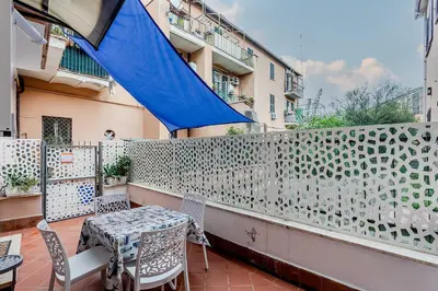 a table and chairs on a balcony with a blue umbrella at Vatican Bridge Home in Rome