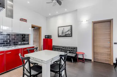 a kitchen with red cabinets and a white table and chairs at Vatican Bridge Home in Rome