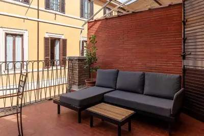 a couch on a balcony with a brick wall at Rasella 21 - FromHometoRome in Rome