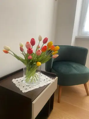 a vase of flowers on a table next to a chair at Appartamento Villa Ada in Rome