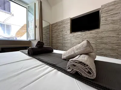 a bedroom with a bed with towels and a flat screen tv at Oasi Floreale - Roma Termini in Rome