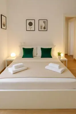 a large white bed with two green pillows on it at Flaminia Design Apartment - GR HOME in Rome