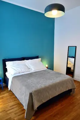 a blue bedroom with a bed and a blue wall at At Home Montebello in Rome