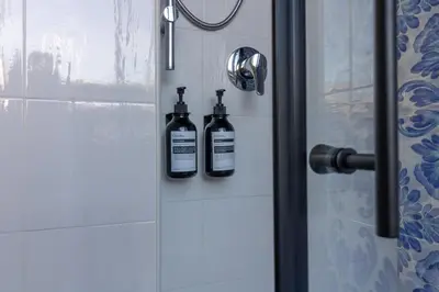 two bottles of alcohol are on the door of a shower at Joe Litty Rooms in Rome