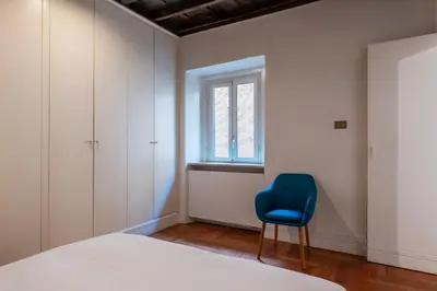 a bedroom with a bed and a blue chair at Frezza 39b - FromeHometoRome in Rome