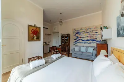 a bedroom with a large white bed and a kitchen at Sales - FromHometoRome in Rome
