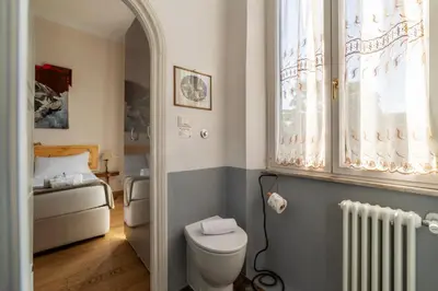 a bathroom with a toilet and a bed and a window at Sales - FromHometoRome in Rome