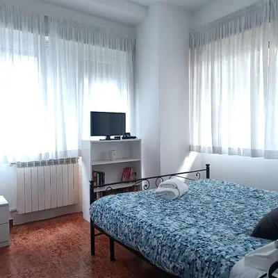 a bedroom with a bed and a tv and windows at Vatican Museums Balcony Apartment - Fast Wi-Fi & Metro Nearby in Rome