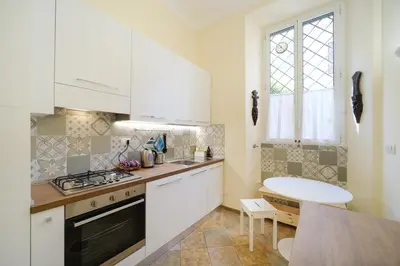 a kitchen with white cabinets and a sink and a table at La Casa del Capitano by BuddyRent in Rome