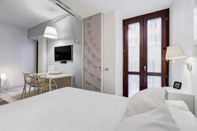a white bedroom with a bed and a desk at Barberini - FromHometoRome in Rome