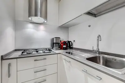 a kitchen with white cabinets and a stainless steel sink at Barberini - FromHometoRome in Rome