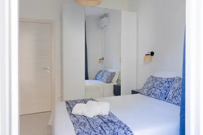 a white bedroom with a bed and a mirror at Nextovatican Apartment in Rome