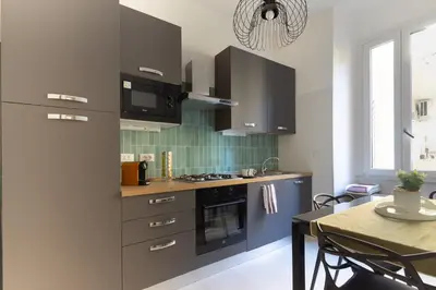 a kitchen with black cabinets and a table with a dining room at Nextovatican Apartment in Rome