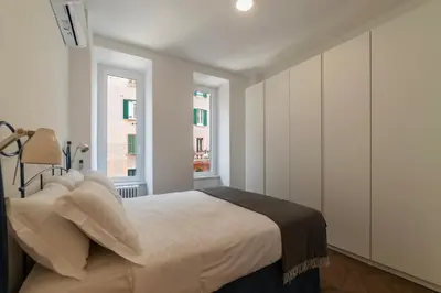 a white bedroom with a bed and two windows at Testaccio - FromHometoRome in Rome