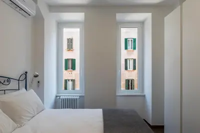 a bedroom with a bed and two windows at Testaccio - FromHometoRome in Rome