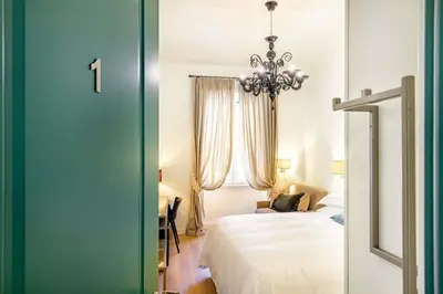 a bedroom with a white bed and a chandelier at Riboty 10 Suites in Rome