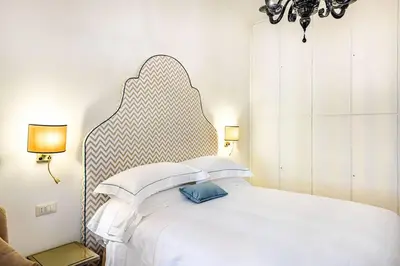 a bedroom with a white bed with a large headboard at Riboty 10 Suites in Rome