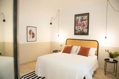 a bedroom with a white bed with orange pillows at Tasso Designer Suite - Colosseum Esquilino in Rome