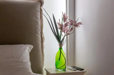a green vase with flowers on a table next to a bed at iFlat Comfy apt a few steps from the Vatican in Rome