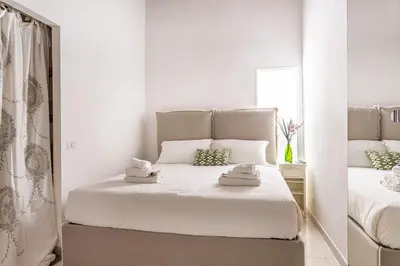 a white bedroom with two beds and a mirror at iFlat Comfy apt a few steps from the Vatican in Rome